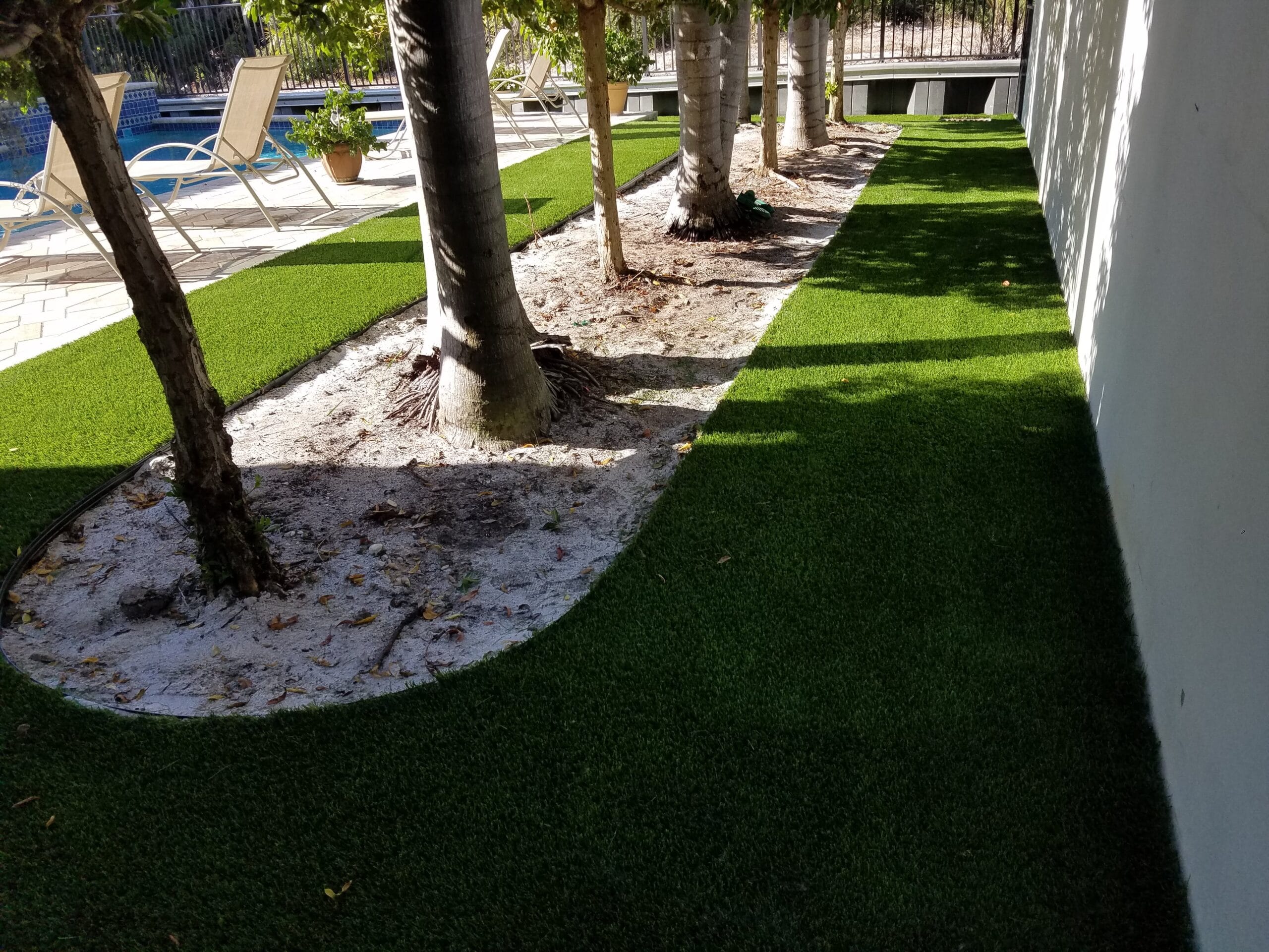 a lawn with trees and a pool in the background smart synthetic turf