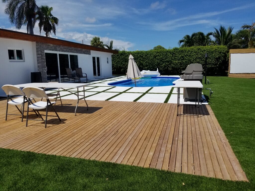 a deck with chairs and a pool in the back smart synthetic turf