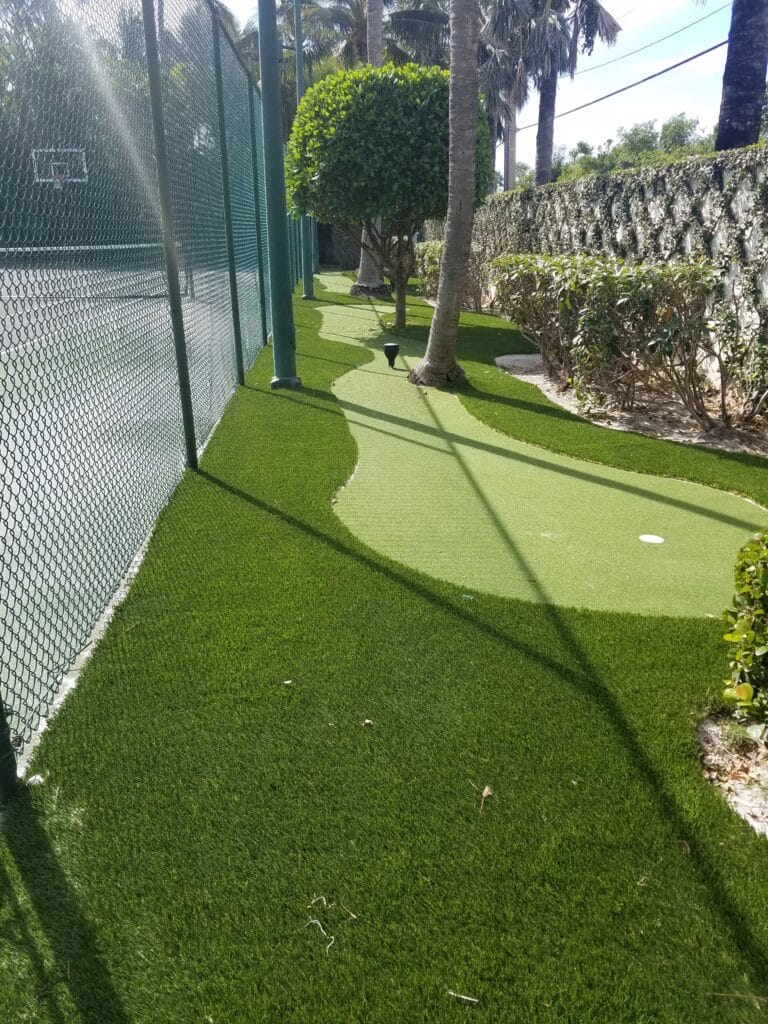 a golf course with a fence and trees smart synthetic turf