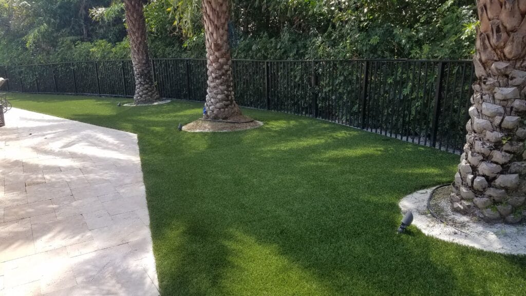 a grass lawn with trees and a fence smart synthetic turf